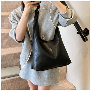 Detail view of stylish black hobo bag with wide strap and shiny leather texture