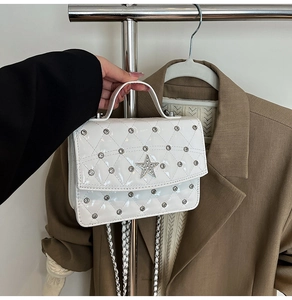 Detail showing white quilted leather bag with silver star studs and chain strap