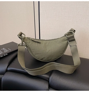 Detail of army green nylon crescent bag with wide fabric strap and zipper closure