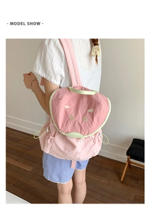 Detail view of pink watermelon backpack with green trim and golden seed accents