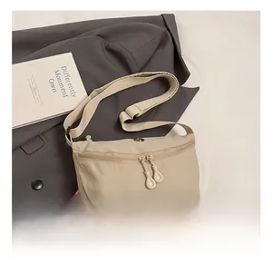 Detail showing apricot nylon crescent bag with double zipper and wide strap on grey suit