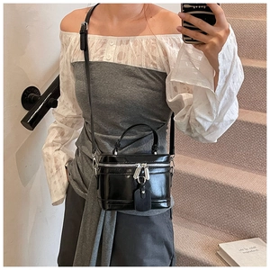 Details einer schwarzen Lackleder-Beuteltasche mit Silber-Reißverschluss und Griff
