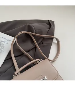 Detail der beigen Kunstledertasche mit silbernen quadratischen Nieten und Schultergurt