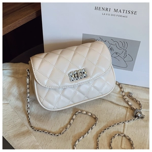 Detailed close-up of quilted cream crossbody bag with silver chain and metal buckle