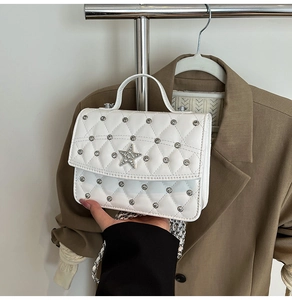 Detail of white quilted handbag with silver studs, rhinestone star, and chain strap
