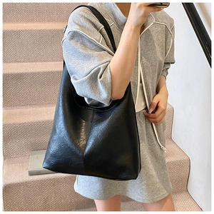 Close-up of a large black tote bag with vertical stitching on smooth faux leather