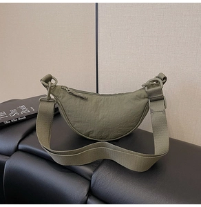 Close-up of olive green nylon crescent bag with textured fabric and matte buckle detail