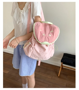 Detailed view of pink watermelon backpack with seed embroidery and green handle