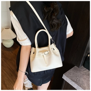 Detailed close-up of woven texture and premium leather stitching on the cream bucket bag
