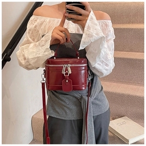 Detail einer dunkelroten Eimertasche mit silbernen Reißverschlüssen und Schultergurt