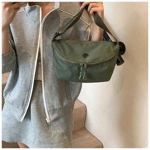 Detail of army green nylon crossbody bag showing metal V logo and dual zipper closure