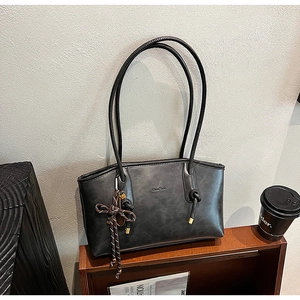 Dettaglio della borsa tote nera vintage con nappina intrecciata e logo dorato