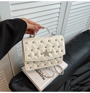 Detail of white quilted handbag with star crystal buckle and silver chain strap