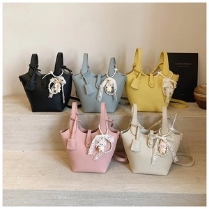 Detail view of colorful leather bucket bags featuring pearl lace charms and crossbody straps