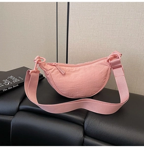 Detail of pink nylon crescent bag with wide adjustable strap and ruffled texture