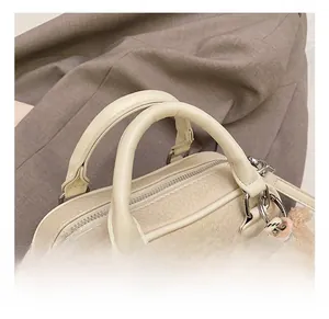 Detail of cream bowling bag showing pebbled leather texture and plush bear charm