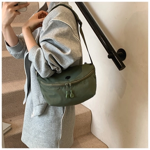 Detail of army green nylon crescent bag with double zippers and black round patch