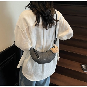 Detail der dunkelgrauen Mondsicheltasche mit Bärchenanhänger, von Model getragen