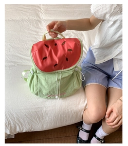 Close-up of watermelon-themed backpack with vibrant green body and seed embroidery