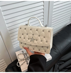 Detail of white quilted crossbody bag with silver studs and a crystal star embellishment
