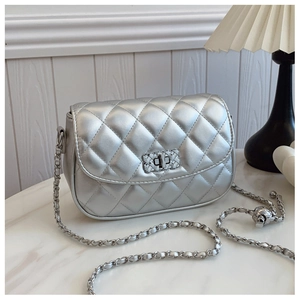 Close-up of silver quilted crossbody bag with metallic finish and woven chain strap detail