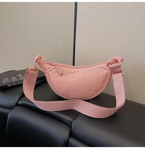 Detail view of pink nylon crescent hobo bag with pleated texture and wide strap