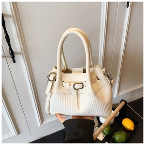 Detail of woven beige leather bucket bag with belt buckle and metal hook accents