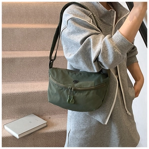 Detail of dark green nylon crescent bag with adjustable strap and double zipper closure