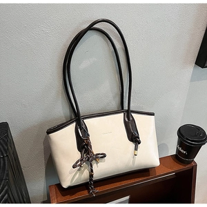 Dettaglio della borsa tote in pelle retrò con ciondolo a nodo e logo in metallo