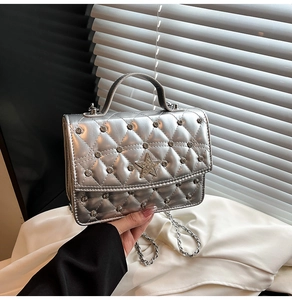 Detailed close-up of a silver quilted handbag with star stud and chic chain strap
