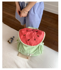 Detailed view of watermelon themed canvas backpack with red flap and seed embroidery