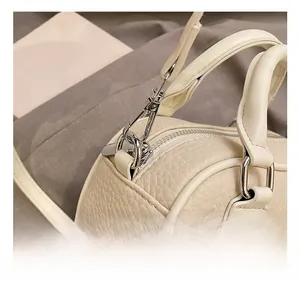 Detailed close-up of silver metal hooks and pebble grain leather on a beige bowling bag