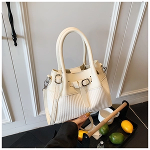 Detail of cream leather tote bag with woven texture and metal buckle accents