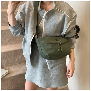 Olive green casual crossbody bag featuring a round logo and wide strap on a model