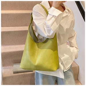 Side view of avocado green bucket bag with wide strap on shoulder of a model