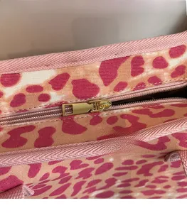 Close-up of golden metal zipper and pink leopard print pattern on large tote bag