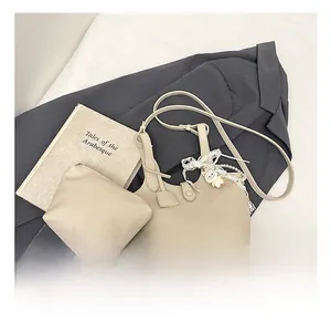 Close-up of cream textured faux leather bucket bag set with elegant lace pearl charm