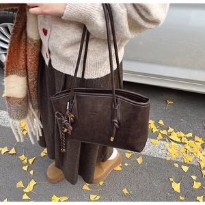 Primo piano della borsa tote marrone scuro con finitura ruvida e dettaglio in corda