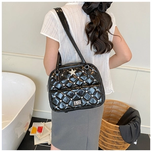 Detail of black quilted patent leather backpack with silver star clasp and metal rivets