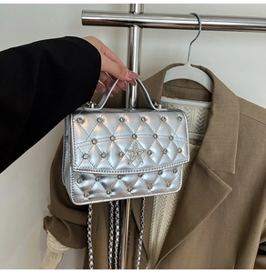 Close-up of silver quilted chain bag with a sparkling star emblem and metallic texture