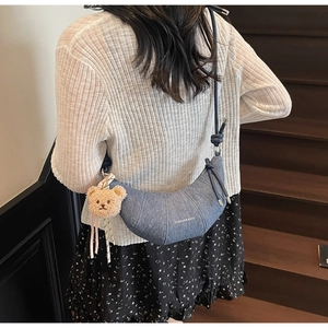 Detail der blauen Denim-Hörnchen-Tasche mit Plüschbär-Anhänger und Knotengurt