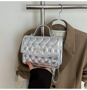 Close-up of silver quilted crossbody bag featuring rhinestone star and metal studs