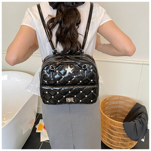 Detail of mini black quilted backpack with star stud decoration on a model