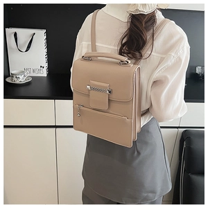 Details des beigen Lederrucksacks mit Metallkette und Nieten, getragen von einem Modell