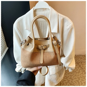 Detail of woven straw bucket bag with beige leather trim and cylindrical top handles
