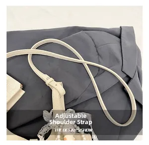 Detail of adjustable strap with lace, pearls and a cute charm on a beige bucket bag