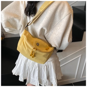 Detail of bright yellow nylon crescent crossbody bag with metal logo and adjustable strap