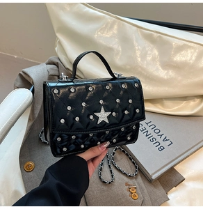 Detail of black quilted leather handbag with sparkling star ornament and silver chain strap