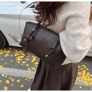 Dettaglio di una borsa tote in pelle marrone con nodi decorativi in un contesto autunnale