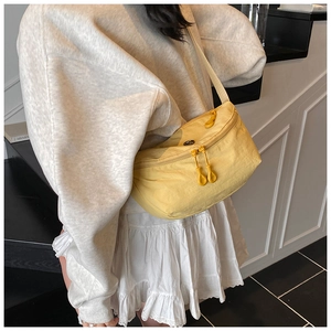 Close-up of vibrant yellow crossbody bag with dual zippers on a casual model outfit